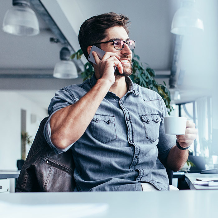 stockphoto man with glasses on phone with mug in hand