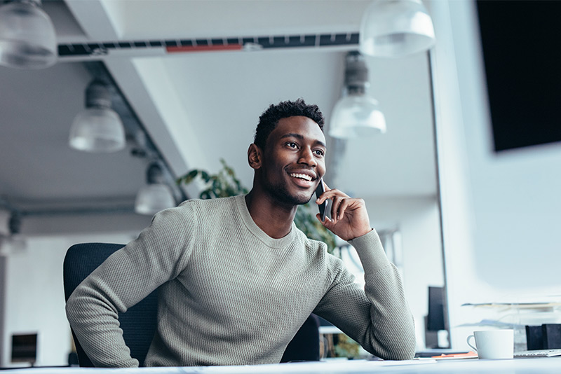 stockphoto african american man at desk smiling on phone