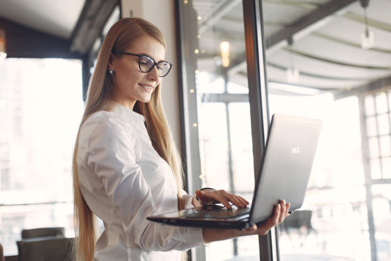 stockphoto woman holding laptop near windows